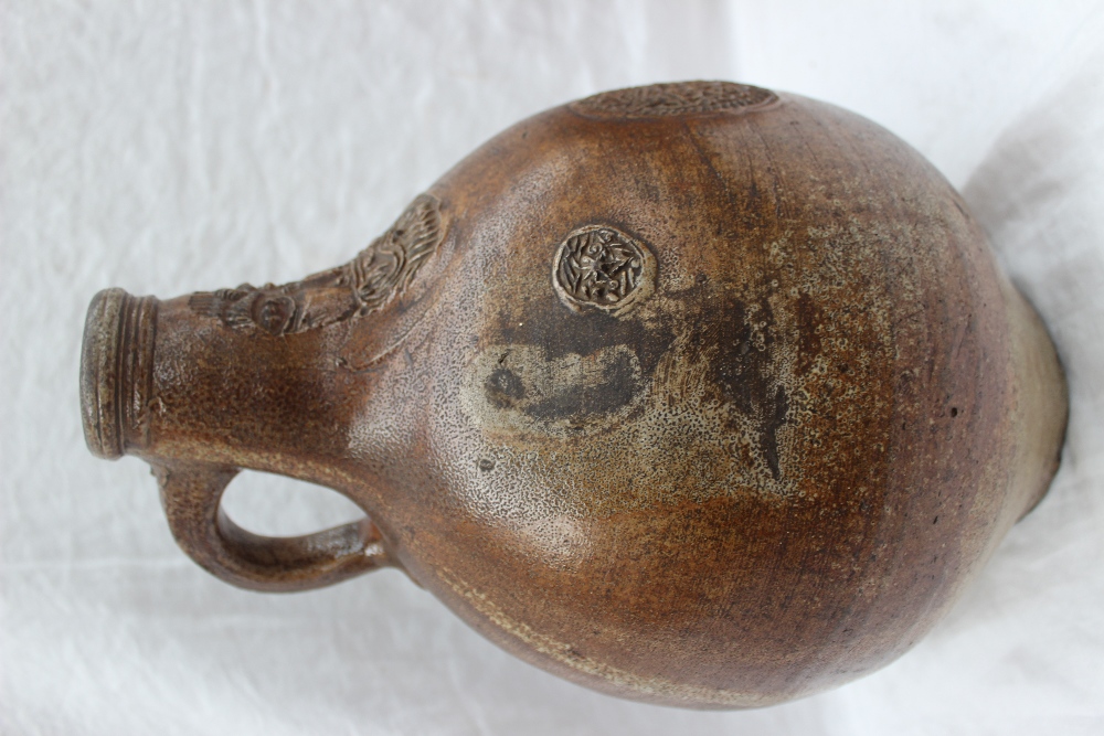 A large 18th century salt glazed Bellarmine mask jug, with a ring handle and finger marks, - Image 6 of 10