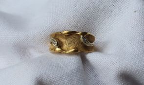 An 18ct yellow gold ring with a tapering textured shank set with two round brilliant cut diamonds,