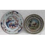 A Delft polychrome decorated plate, painted to the centre with houses by a river,