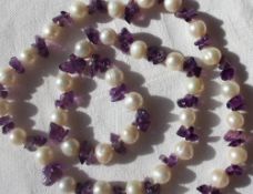 A pearl and amethyst necklace set with thirty five pearls and amethyst chips to a lobster claw