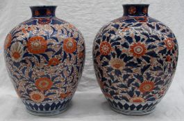 A pair of Japanese Imari vases, decorated with flowerheads and leaves,