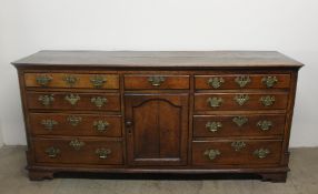 An 18th century North Wales oak dresser base, the rectangular planked top with cut corners,