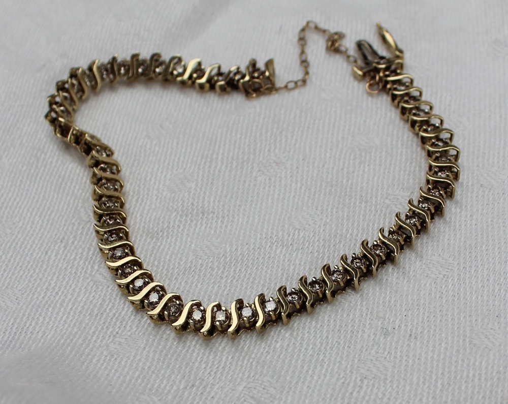 A 9ct yellow gold diamond set tennis bracelet, with S shaped links, approximately 9.