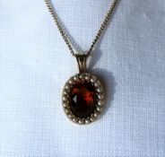 A 15ct gold citrine and seed pearl pendant set with an oval faceted citrine surrounded by seed