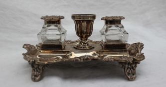 A late Victorian silver desk standish, with a central urn and two glass and silver topped inkwells,