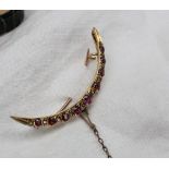 A ruby and diamond crescent shaped brooch set with nine round faceted rubies and ten diamonds to a