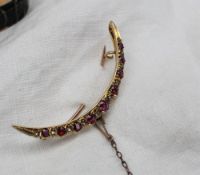 A ruby and diamond crescent shaped brooch set with nine round faceted rubies and ten diamonds to a
