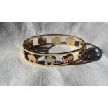 A three colour 9ct gold hinged bangle decorated with elephants,