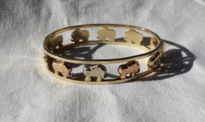 A three colour 9ct gold hinged bangle decorated with elephants,
