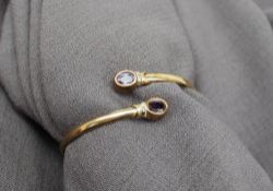 A 9ct yellow gold bangle, set with two oval faceted amethysts,