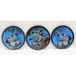 A set of three Japanese cloisonne enamel chargers decorated with cranes in flight with flowers and