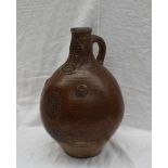 A large 18th century salt glazed Bellarmine mask jug, with a ring handle and finger marks,