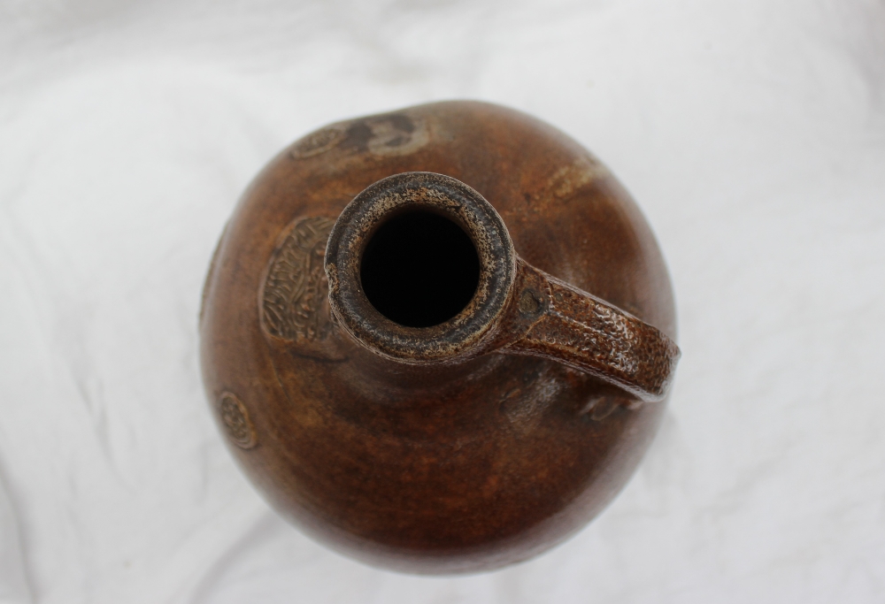 A large 18th century salt glazed Bellarmine mask jug, with a ring handle and finger marks, - Image 9 of 10