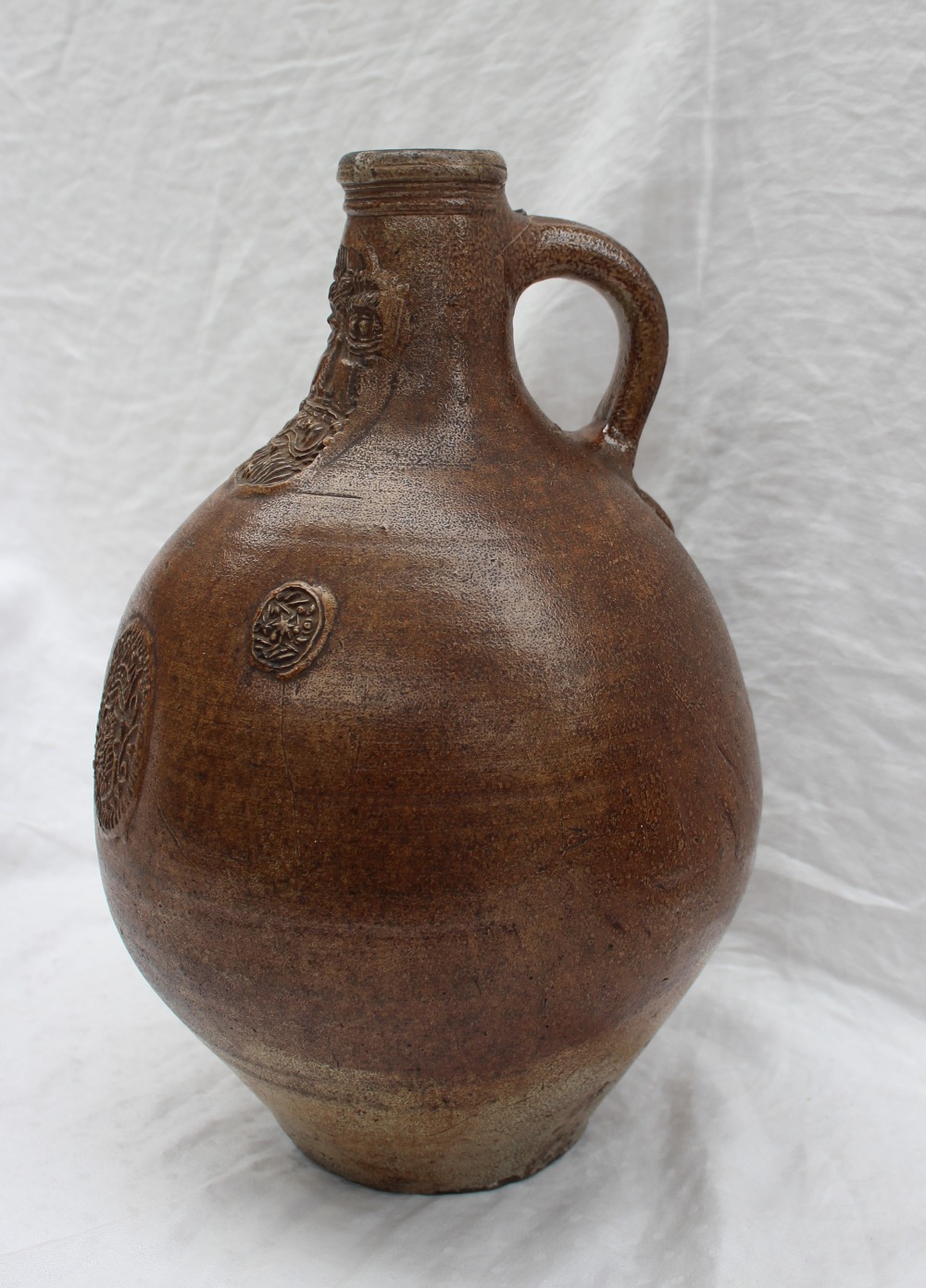 A large 18th century salt glazed Bellarmine mask jug, with a ring handle and finger marks, - Image 2 of 10