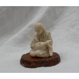 A late 19th century Japanese ivory figure depicting an elderly gentleman with glasses seated cross