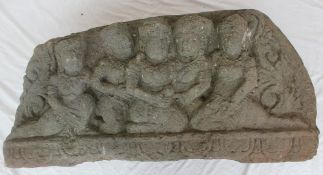 A carved reconstituted stone panel depicting Indian figures in a line on a lotus leaf carved base,