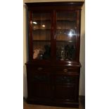 An Edwardian walnut bookcase the moulded dentil cornice above a pair of glazed doors,