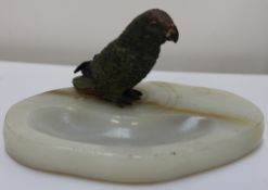 A cold painted bronze parrot perched on an onyx ashtray base