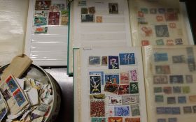 Three stamp albums together with a tin of stamps containing world stamps