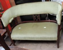 An Edwardian mahogany two seater settee with an arched upholstered back and lattice splats