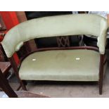 An Edwardian mahogany two seater settee with an arched upholstered back and lattice splats