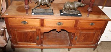 A pine dresser base with a rectangular top above drawers and cupboards with a central dog kennel on