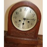 An oak cased mantle clock of domed form with a silvered dial and Arabic numerals