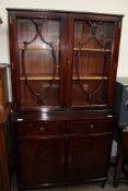 A reproduction mahogany bookcase with glazed doors to the top and cupboards and drawers to the base