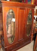 An Edwardian mahogany triple wardrobe with a pair of mirrored doors and two drawers,