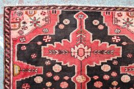 A Hand woven Hamadan rug with stylised flowers to a red ground