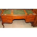 A reproduction desk with three leather inset panels above five drawers on cabriole legs and