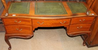 A reproduction desk with three leather inset panels above five drawers on cabriole legs and