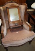 A continental upholstered wing back arm chair together with a hanging mirrored cabinet