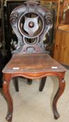 A Victorian mahogany hall chair with a shield shaped back and solid seat