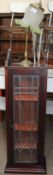 A hanging wall cabinet with a leaded glazed door together with a table lamp