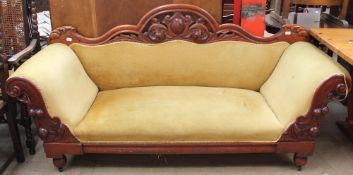 A Victorian walnut scroll arm settee with a shield and leaf carved back