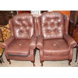 A pair of brown leather wing back elbow chairs