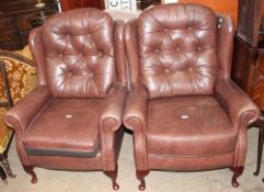 A pair of brown leather wing back elbow chairs