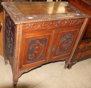 A continental walnut washstand with a hinged carved top above a pair of cupboard doors on turned