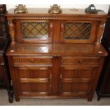 A 20th century oak court cupboard with glazed doors to the top and cupboards and drawers to the