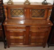 A 20th century oak court cupboard with glazed doors to the top and cupboards and drawers to the