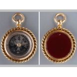 A 9CT YELLOW GOLD FOB AND COMPASS, of circular form with rope frame, one side set with carnelian,