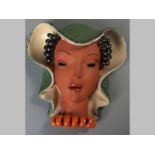 A CZECHOSLOVAKIAN CERAMIC WALL MASK, lady with black spiral hair and green bonnet, red spiral