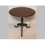 A VICTORIAN MAHOGANY TILT-TOP TABLE, the circular top with a carved moulding, standing on a baluster