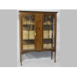 AN EDWARDIAN MAHOGANY DISPLAY CABINET, the arched glazed doors flanking a marquetry panel with