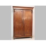 A VICTORIAN MAHOGANY LINEN PRESS, the moulded pediment above two arched panelled doors opening to