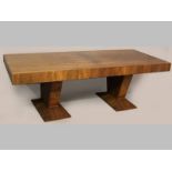 AN ART DECO WALNUT DINING TABLE, Circa 1930's, the quartered top above a broad frieze, standing on