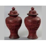 A PAIR OF CHINESE RED CINNABAR LACQUER BALUSTER VASES AND COVERS, heavily carved with scenes of