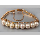 AN 18CT YELLOW GOLD AND PEARL BRACELET, eight pearls mounted on a scroll gold frame, each side