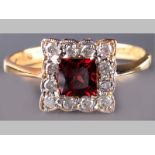 AN 18CT WHITE GOLD, YELLOW GOLD, DIAMOND AND GARNET RING, square claw set centre garnet surrounded